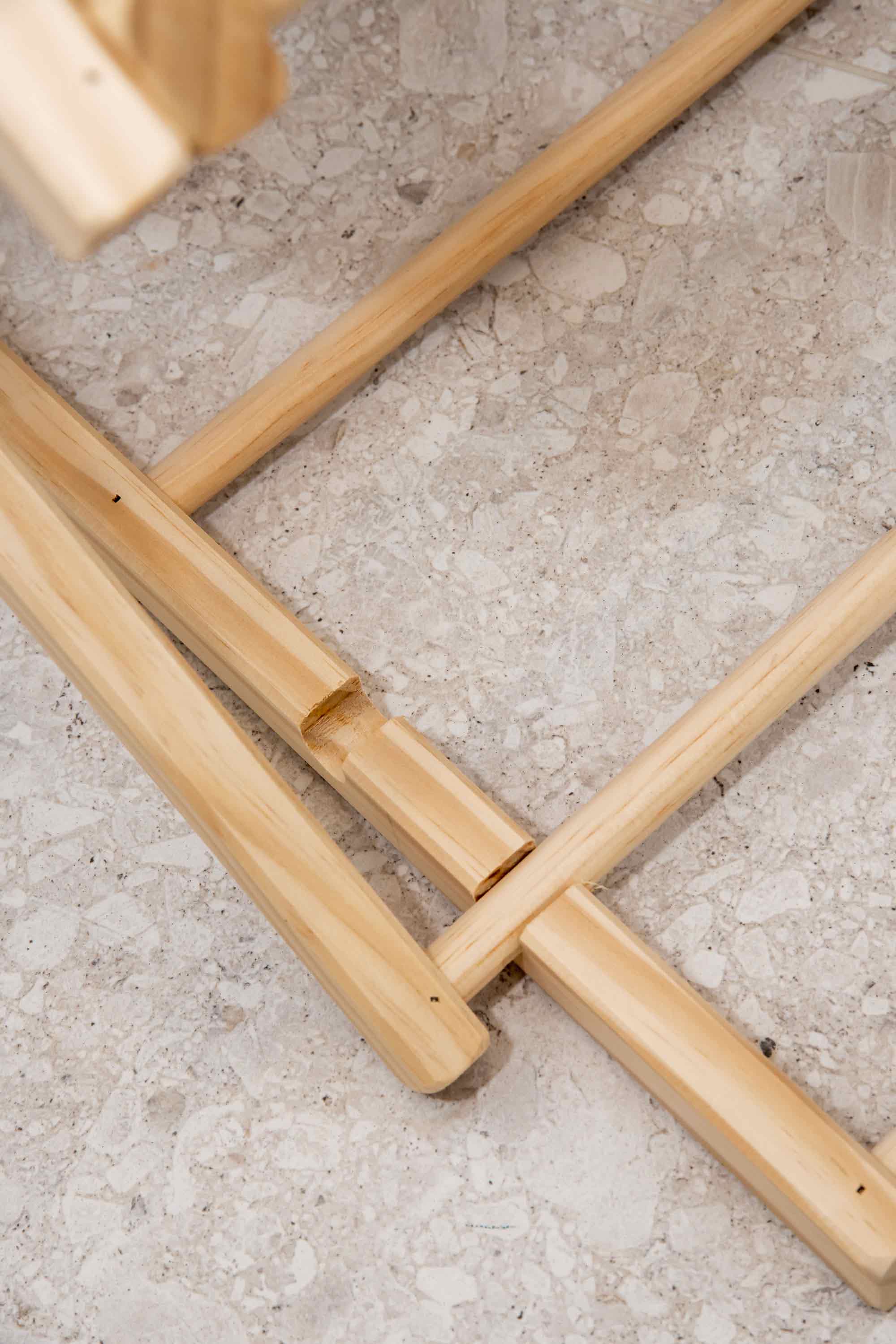 Wooden chair legs on a concrete floor. Victoria James Home Eco Deluxe Clothes Airer