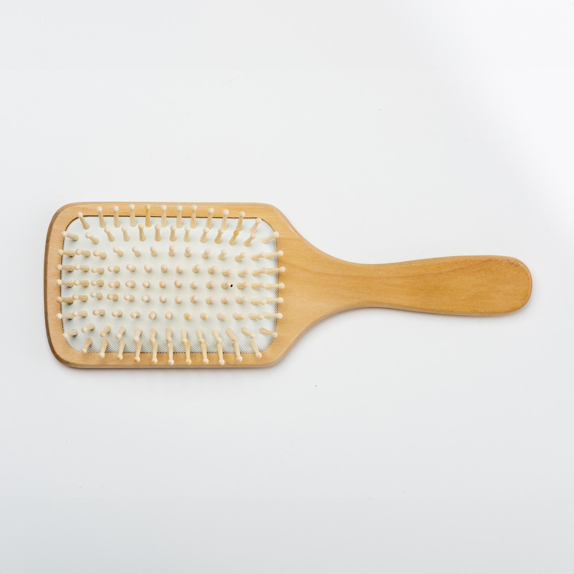 Wooden paddle brush on a light gray background. Victoria James Wooden Paddle Hair Brush