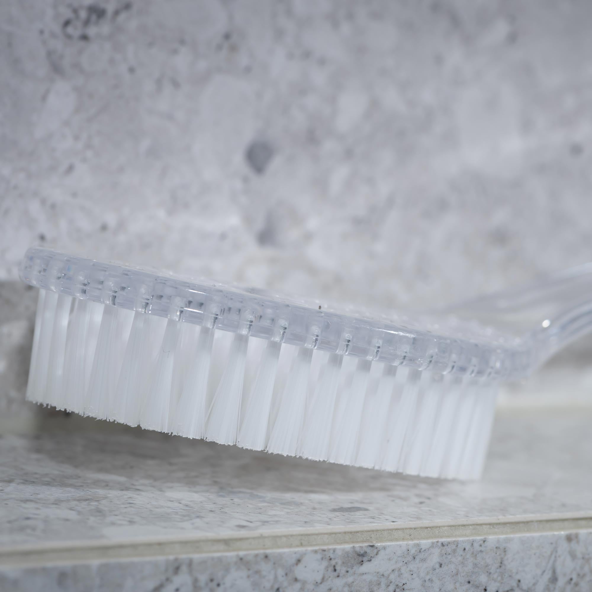 Clear plastic comb on a marble surface. Victoria James Body Bath & Shower Brush
