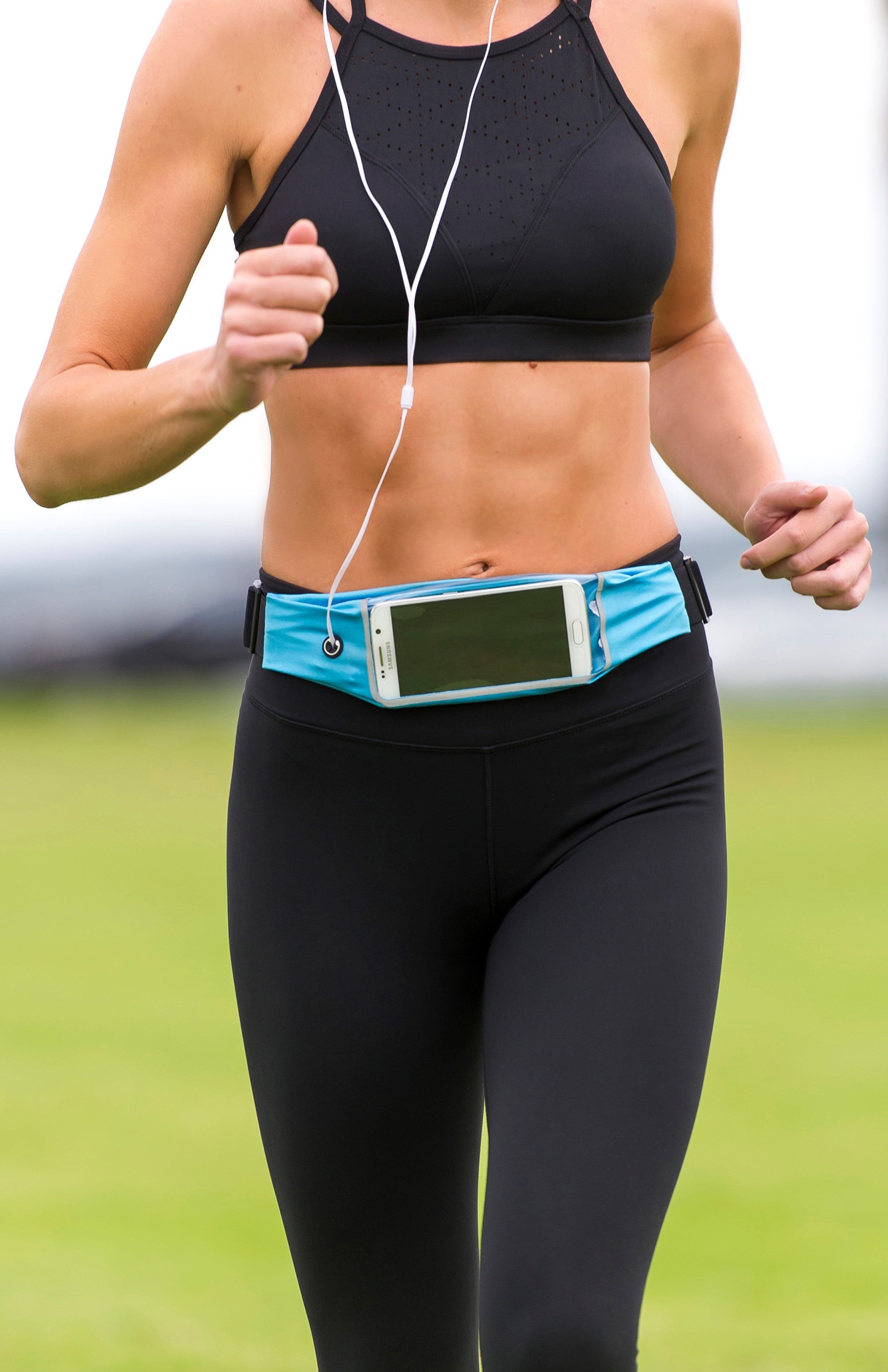 Person running outdoors wearing a black sports bra and leggings with a blue Simply Clean Active Waistband